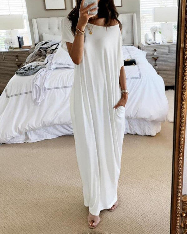 Woman in a white dress standing in a bedroom.