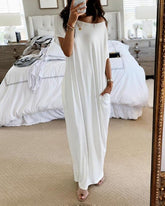Woman in a white dress standing in a bedroom.