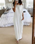 Woman in a white dress standing in a bedroom.