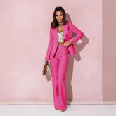 Woman in a pink suit standing against a pink background