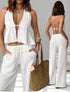 Woman wearing a white outfit with a straw bag, standing against a neutral background.