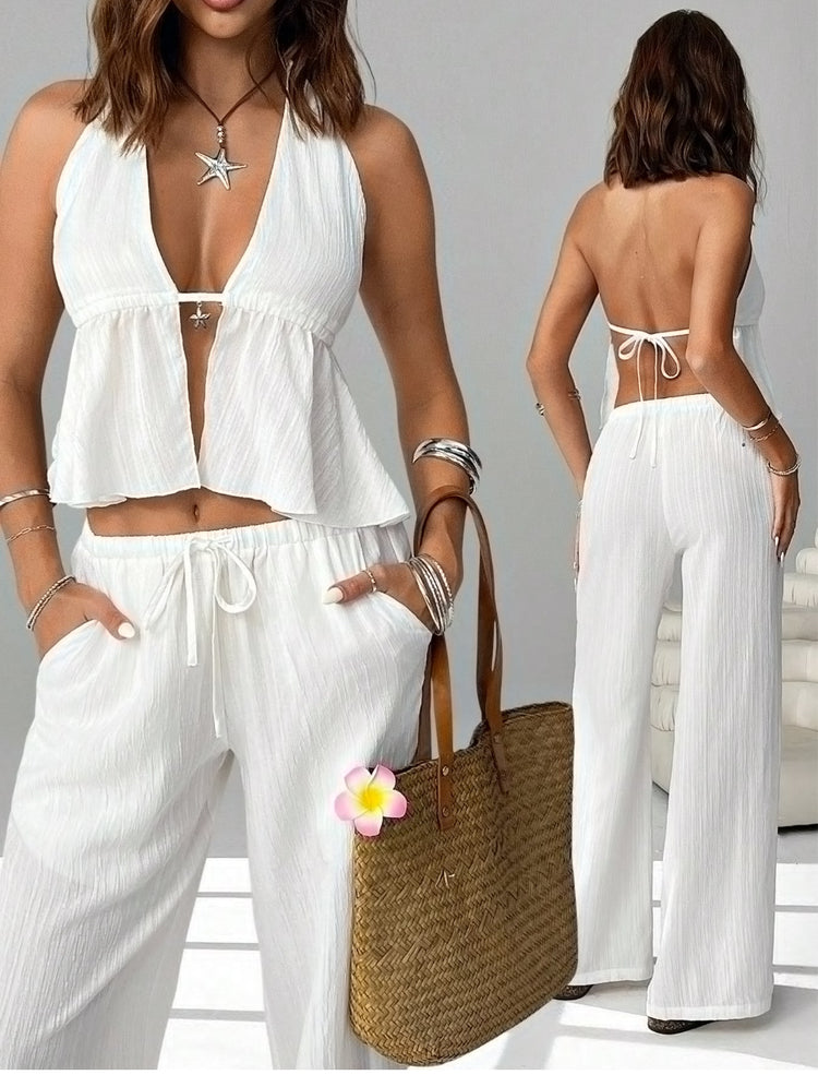 Woman wearing a white outfit with a straw bag, standing against a neutral background.