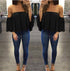 Woman wearing a black off-shoulder top and blue jeans in a fitting room.