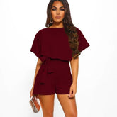 Woman wearing a burgundy romper on a white background