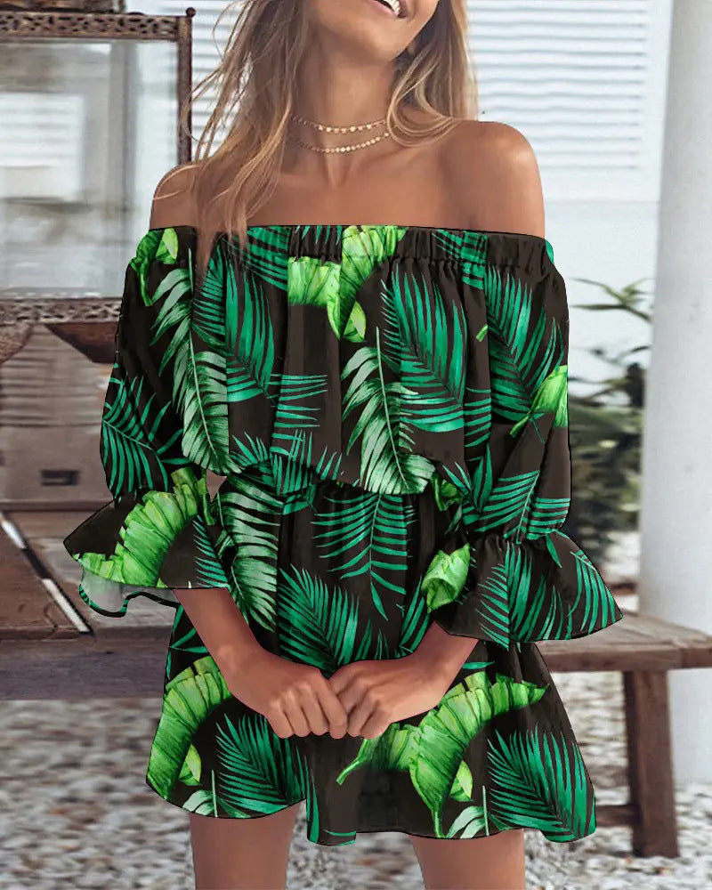 Woman wearing a green and black leaf-patterned dress in an outdoor setting.