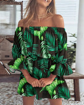 Woman wearing a green and black leaf-patterned dress in an outdoor setting.