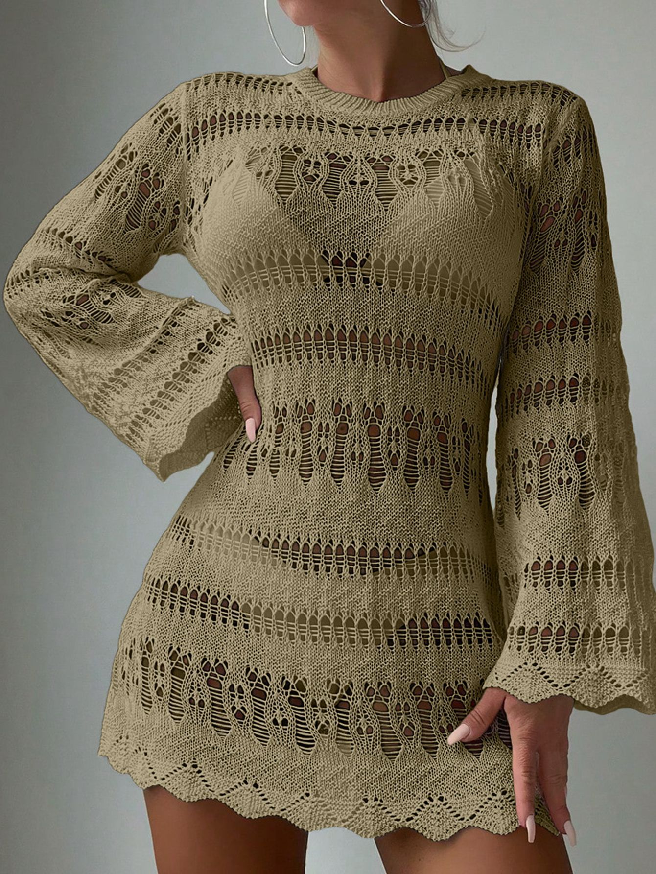 Woman wearing a beige crochet dress against a gray background
