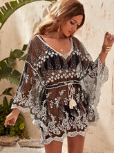 Woman wearing a black and white embroidered cover-up against a natural background