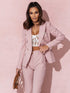 Woman wearing a pink suit with a white lace top against a pink background