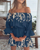 Woman wearing a blue off-shoulder dress with white floral pattern indoors.