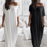 Two women wearing off-shoulder maxi dresses, one white and one black, in a bright room.