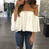 Person wearing a white off-shoulder top and blue jeans in a store setting.