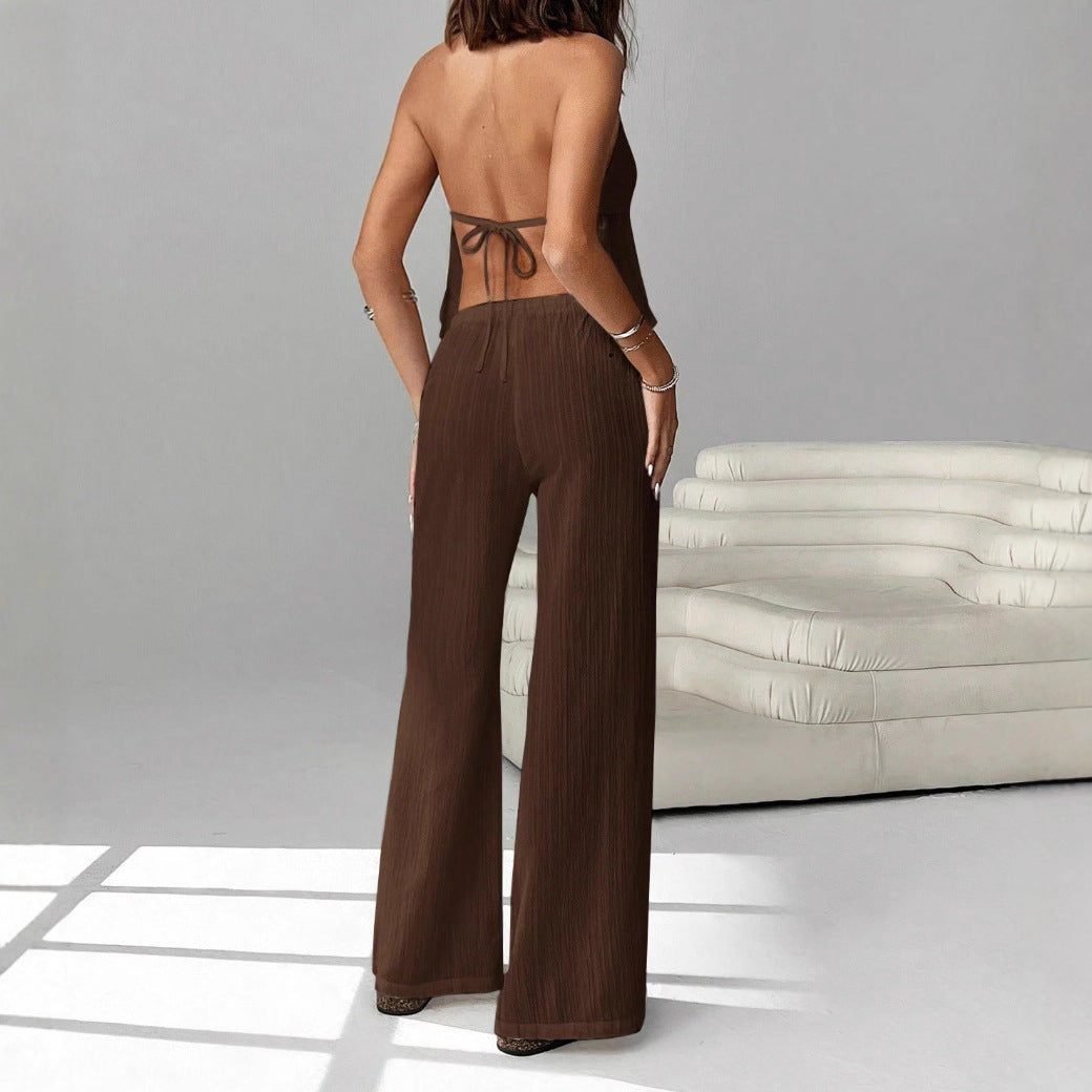 Person wearing a brown outfit with wide-leg pants and a backless top in a minimalistic setting.