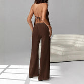 Person wearing a brown outfit with wide-leg pants and a backless top in a minimalistic setting.