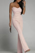 Woman wearing a pink strapless jumpsuit against a gray background