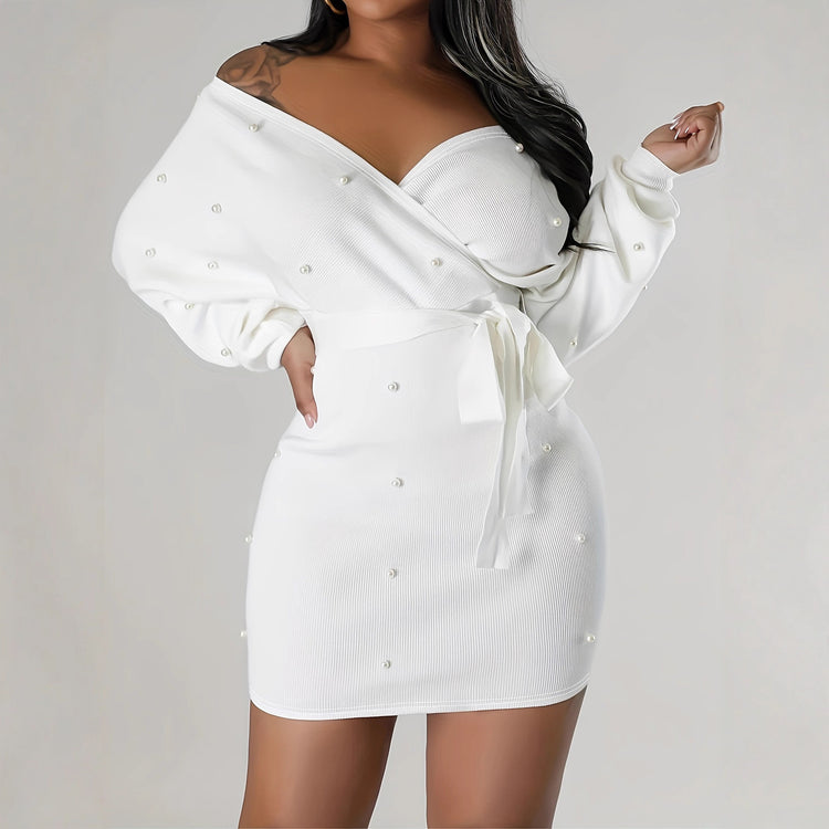 White dress with pearl embellishments on a plain background