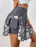 Gray floral skirt with a pocket holding a phone against a white background