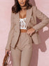 Woman wearing a beige suit with a white lace top against a pink background