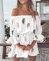 Woman wearing a white off-shoulder dress with feather pattern in an outdoor setting