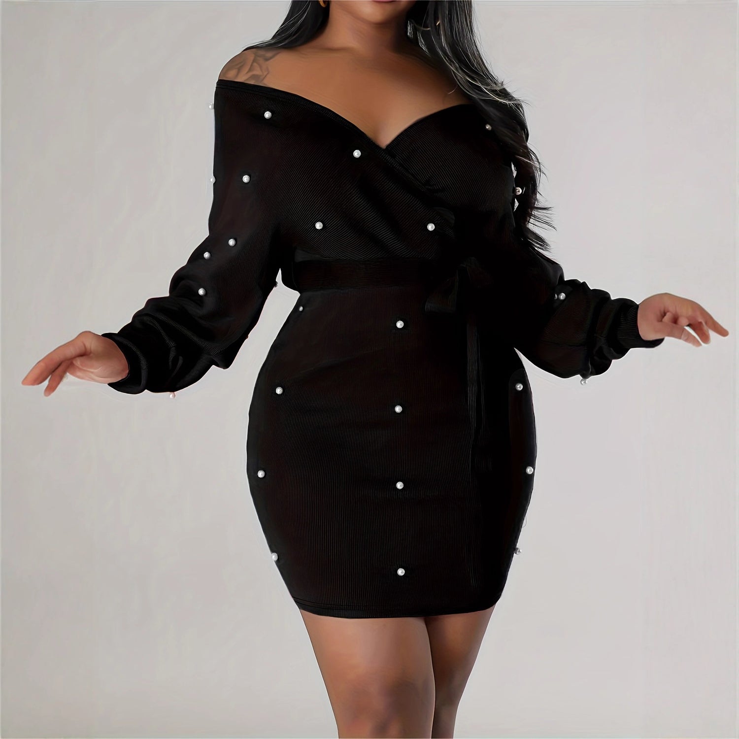 Black dress with pearl embellishments on a plain background