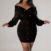 Black dress with pearl embellishments on a plain background