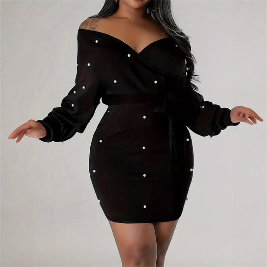 Black dress with pearl embellishments on a plain background