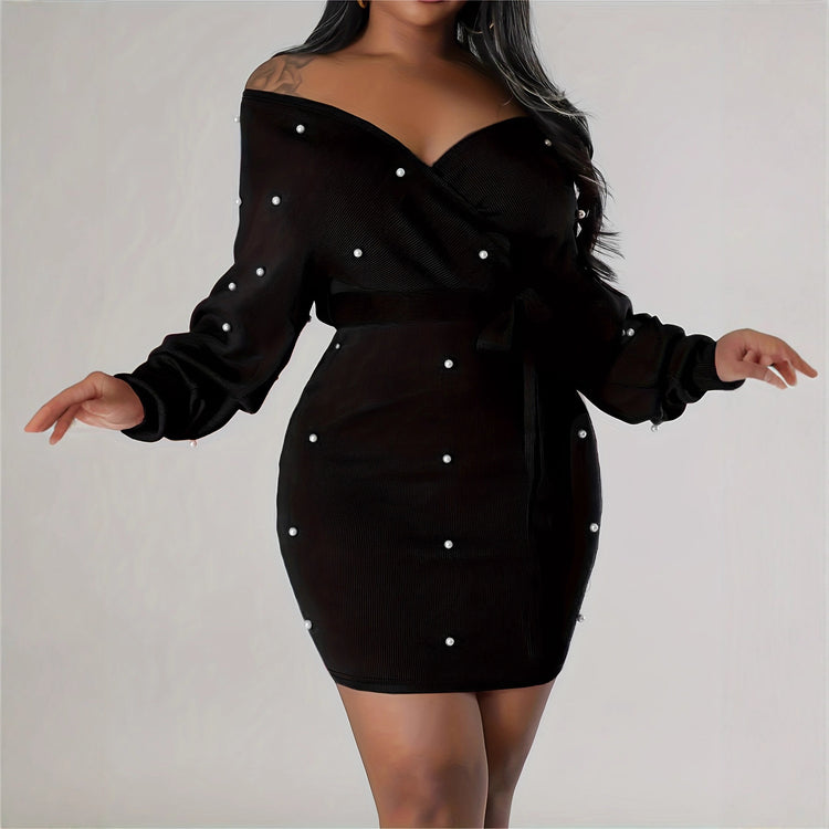 Black dress with pearl embellishments on a plain background
