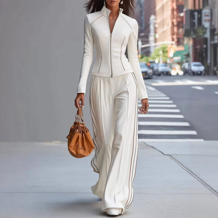 Woman in a white outfit with a brown handbag walking on a city street.
