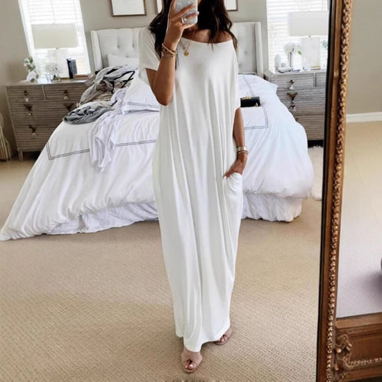 Person wearing a white dress standing in a bedroom.