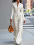 Person wearing a white outfit with a brown handbag on a city street.