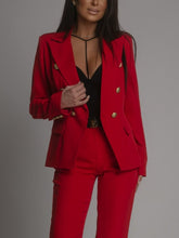 Red suit with gold buttons worn by a person on a gray background