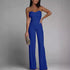 Woman wearing a blue strapless jumpsuit against a gray background