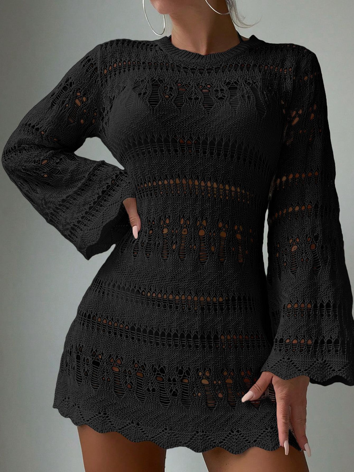 Black crochet dress worn by a person on a plain background