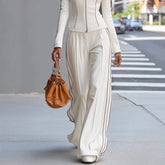 Person wearing a white outfit with a brown handbag on a city street.