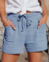Person wearing blue shorts with a white top on a blurred background