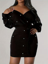 Black dress with pearl embellishments on a plain background
