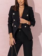 Person wearing a black blazer with silver buttons on a pink background