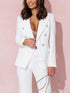Woman wearing a white suit with gold buttons against a pink background