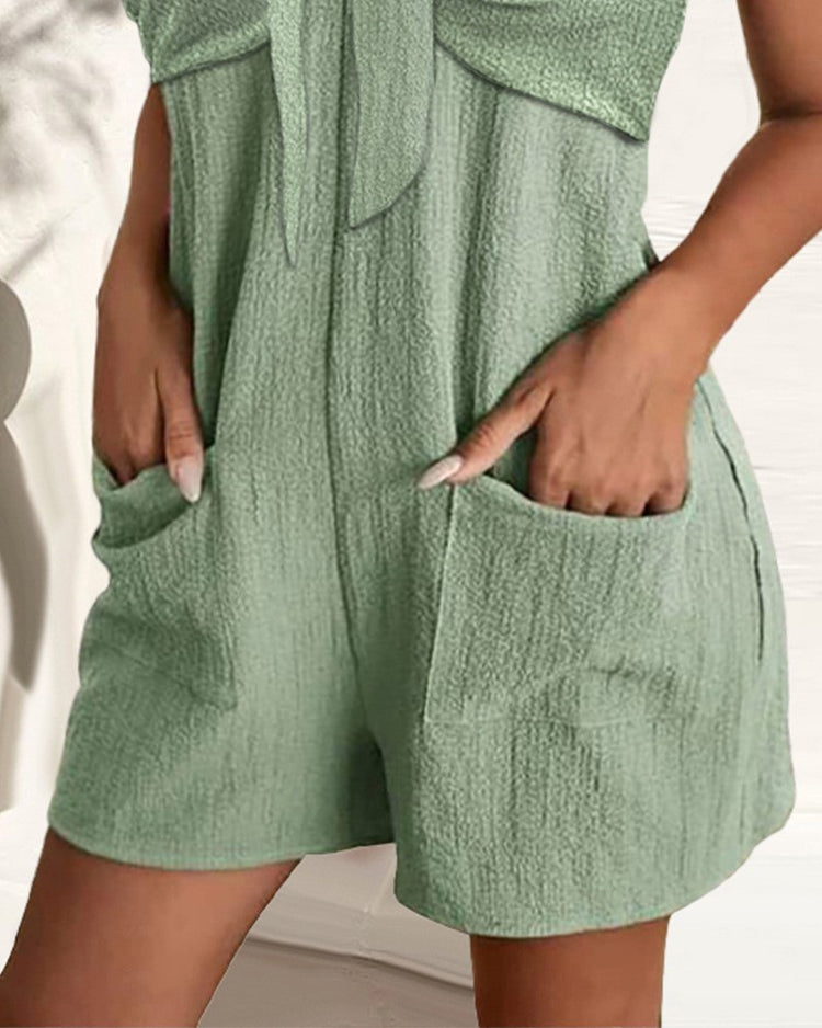 Green textured romper with pockets on a neutral background
